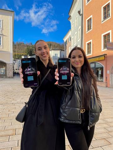 Zwei Frauen präsentieren die Storyminer App auf ihren Smartphones