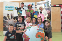 FairTrade Clown Hugo mit Florian Scheicher, Rosa Bock und den Kindern der VS Stadt, die „un-sere Welt“ in Händen halten.